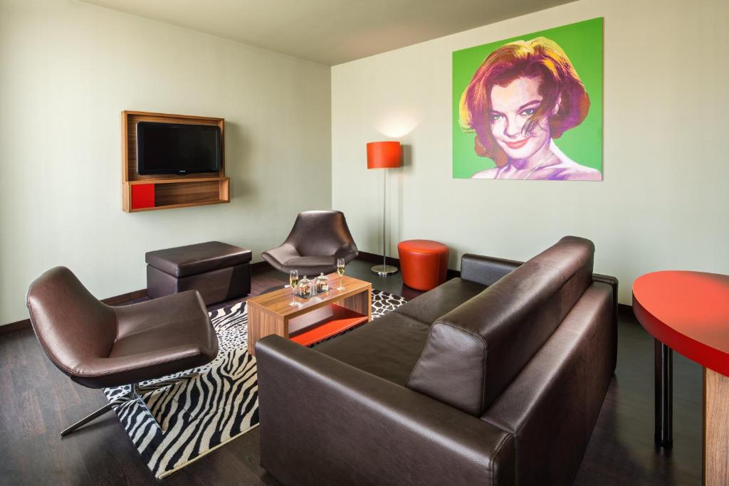 a living room with a couch and chairs and a tv at Clarion Congress Hotel Bratislava in Bratislava