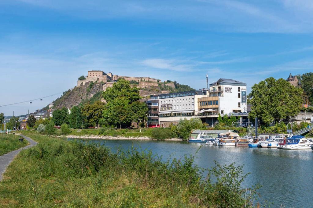 Blick auf einen Fluss mit Gebäuden auf einem Hügel in der Unterkunft Diehls Hotel in Koblenz