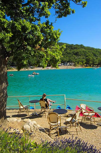 mężczyzna siedzący na plaży obok wody w obiekcie Camping 3etoiles Lac DE STE CROIX GORGES DU VERDON MOUSTIERS STE MARIE ACTVITES NAUTIQUES RANDONNEES w mieście Sainte-Croix-de-Verdon