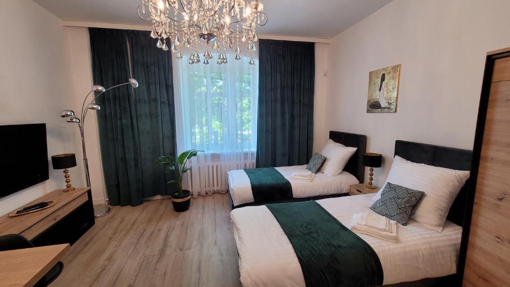 a hotel room with two beds and a chandelier at GOOD DAY APARTMENT centrum Katowice in Katowice