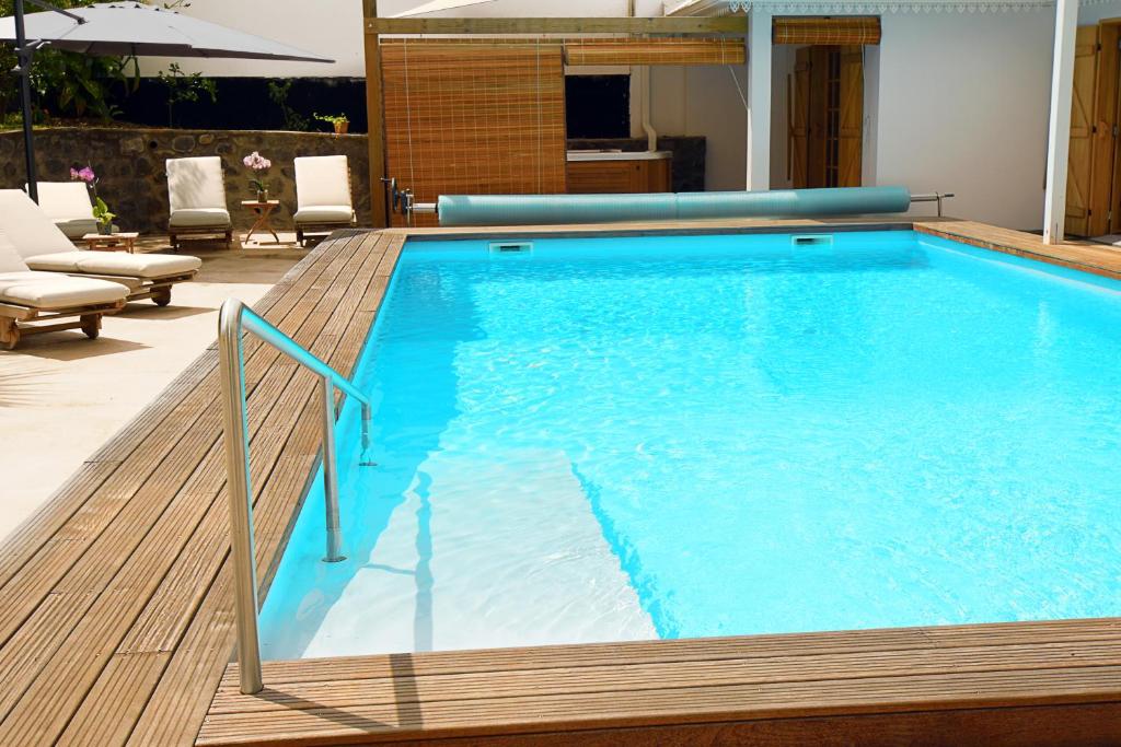 una gran piscina azul con terraza de madera en le Jacaranda du Guillaume, en Le Guillaume
