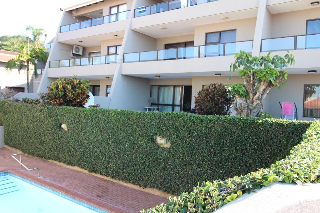 ein Gebäude mit einer Hecke vor einem Swimmingpool in der Unterkunft Corona Del Mar 13 in Margate