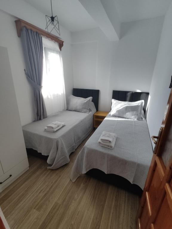 two beds in a room with a window at Apart Turgutreis in Turgutreis