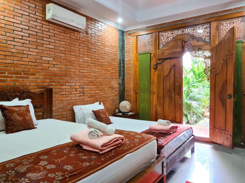 een slaapkamer met 2 bedden en een bakstenen muur bij Ndalem Suryo Saptono Guest House in Yogyakarta