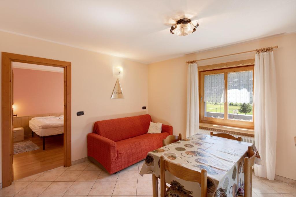 salon z czerwonym krzesłem i stołem w obiekcie Appartamento Valleverde w Livigno