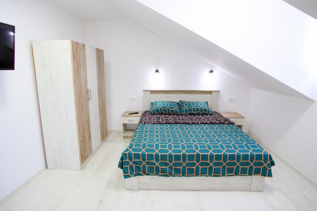 um quarto com uma cama com uma colcha azul e verde em Apartmani Hedonist em Sokobanja