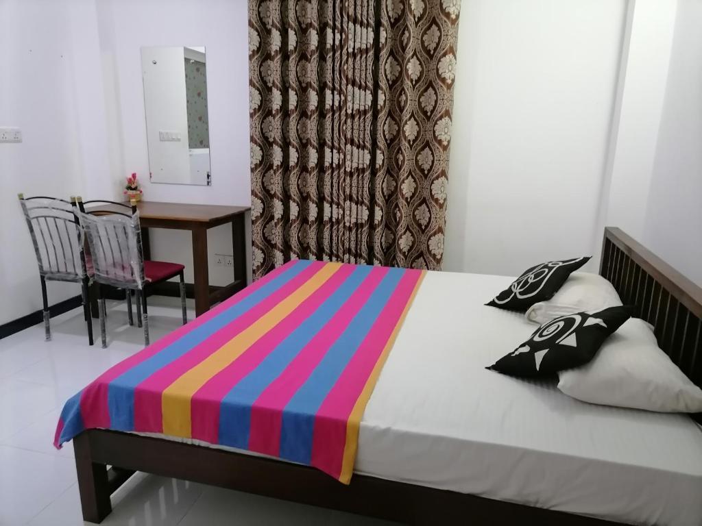 Nesh Villa في ألوثغاما: غرفة نوم مع سرير وبطانية مخططة ملونة