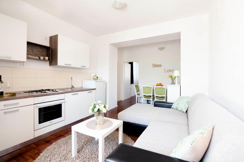 a white living room with a couch and a kitchen at Apartment Alkar in Sinj