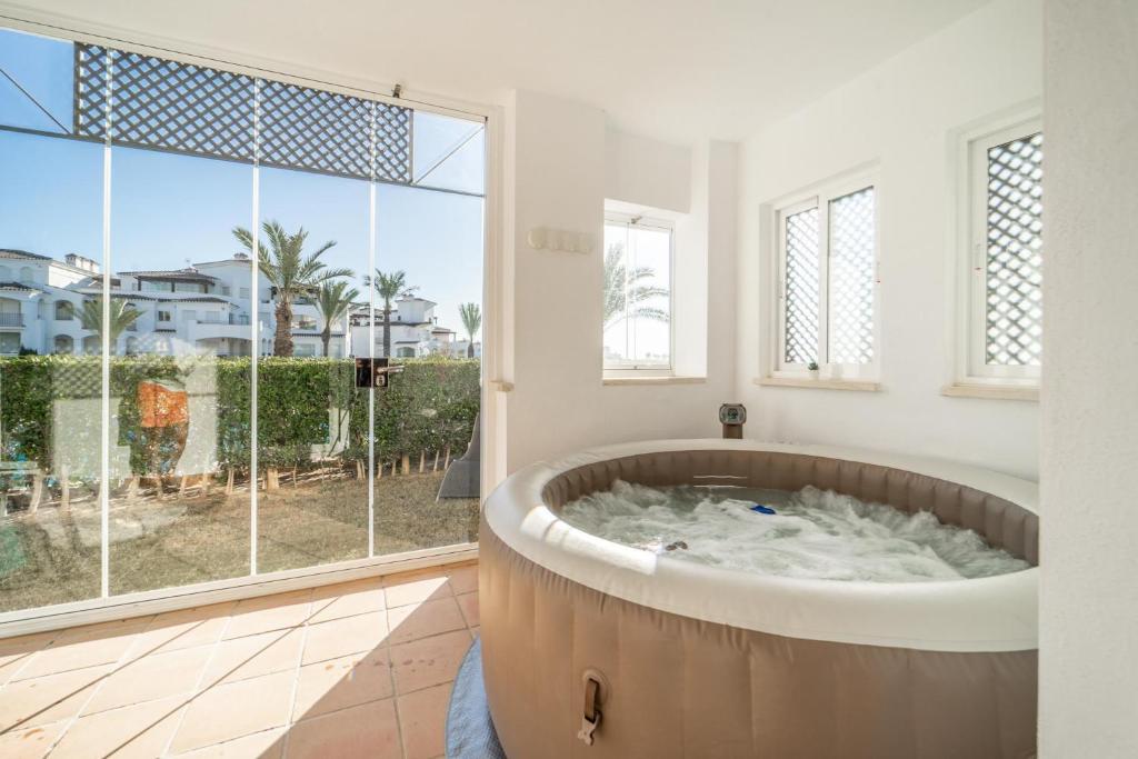 una vasca da bagno in una stanza con una grande finestra di Garden Apartment with Hot Tub - ER2104LT a Torre-Pacheco