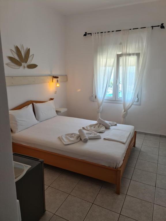 a bedroom with a bed with white sheets and a window at Mar Adentro in Patitiri