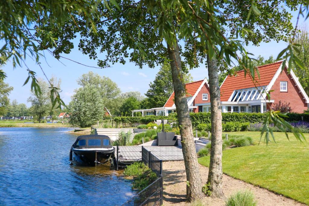 ein Haus am Fluss mit einem Boot am Ufer in der Unterkunft EuroParcs Bad Hoophuizen in Hulshorst