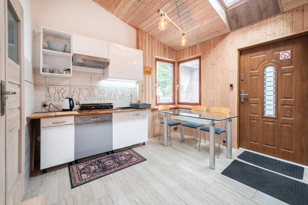une cuisine avec des placards blancs, une table et une porte dans l'établissement Willa Ewa, à Jastarnia