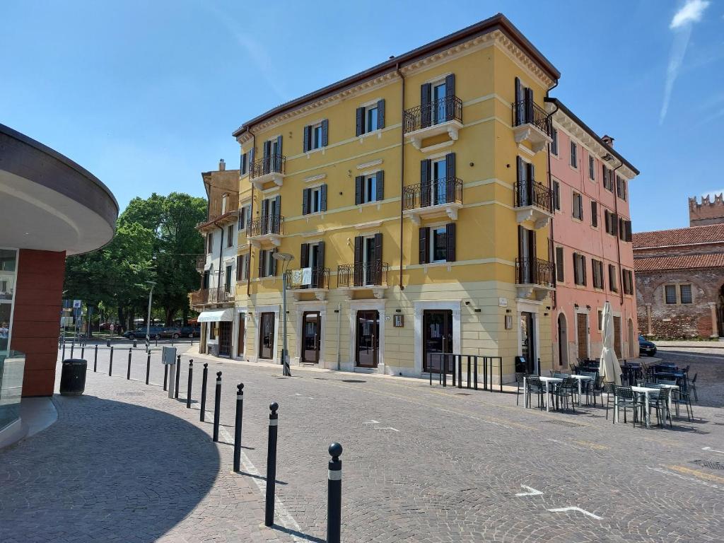 a large yellow building on a street with tables and chairs at HomeThirtyFour in Verona