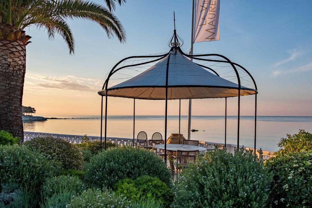 a table with an umbrella in front of the ocean at La Villa Mauresque in Saint-Raphaël
