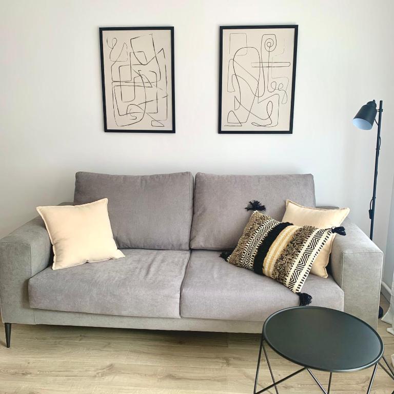 ein Wohnzimmer mit einem grauen Sofa mit Kissen und einem Tisch in der Unterkunft New Apartment La Massana - Telecabina to Bike Park in La Massana