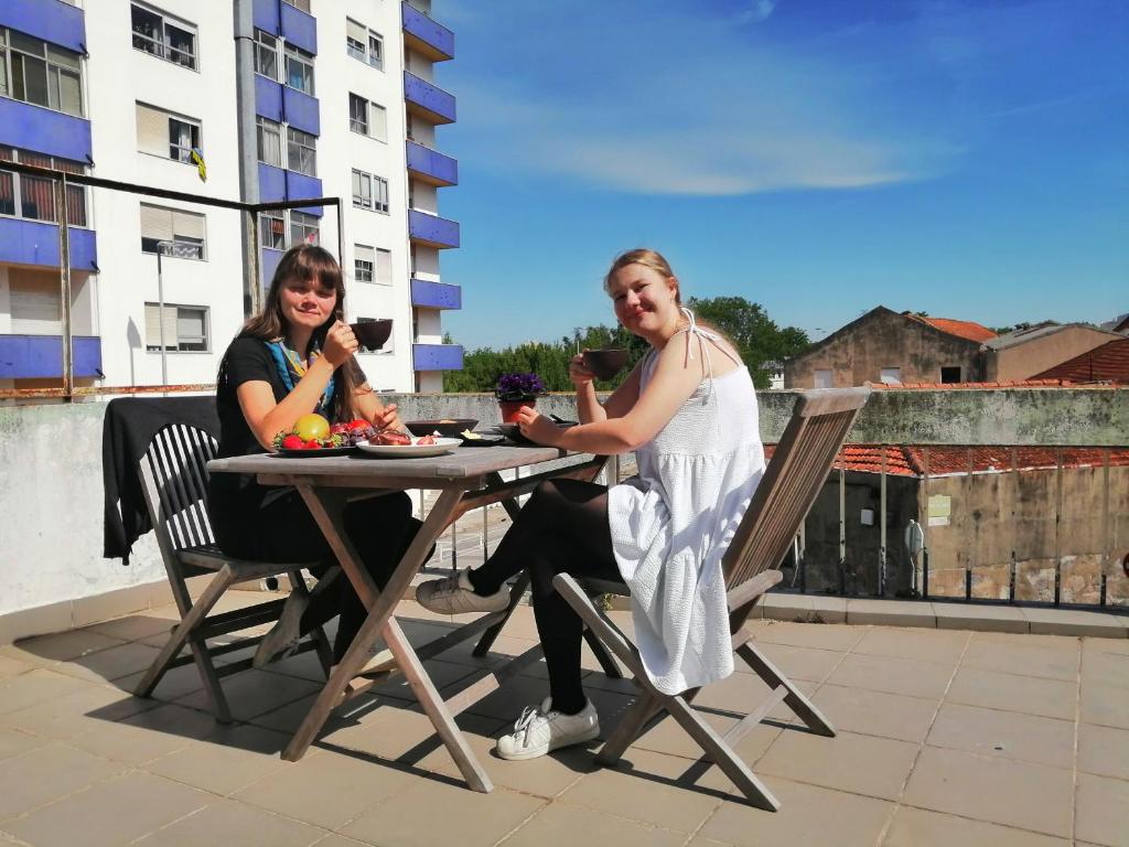 two women sitting at a table on a roof at Rooms São Dinis in Porto