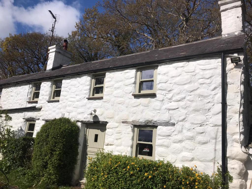 a white stone house with a black roof at Animal Sanctuary Holiday Pen Bryn Twrw - Charity in Conwy