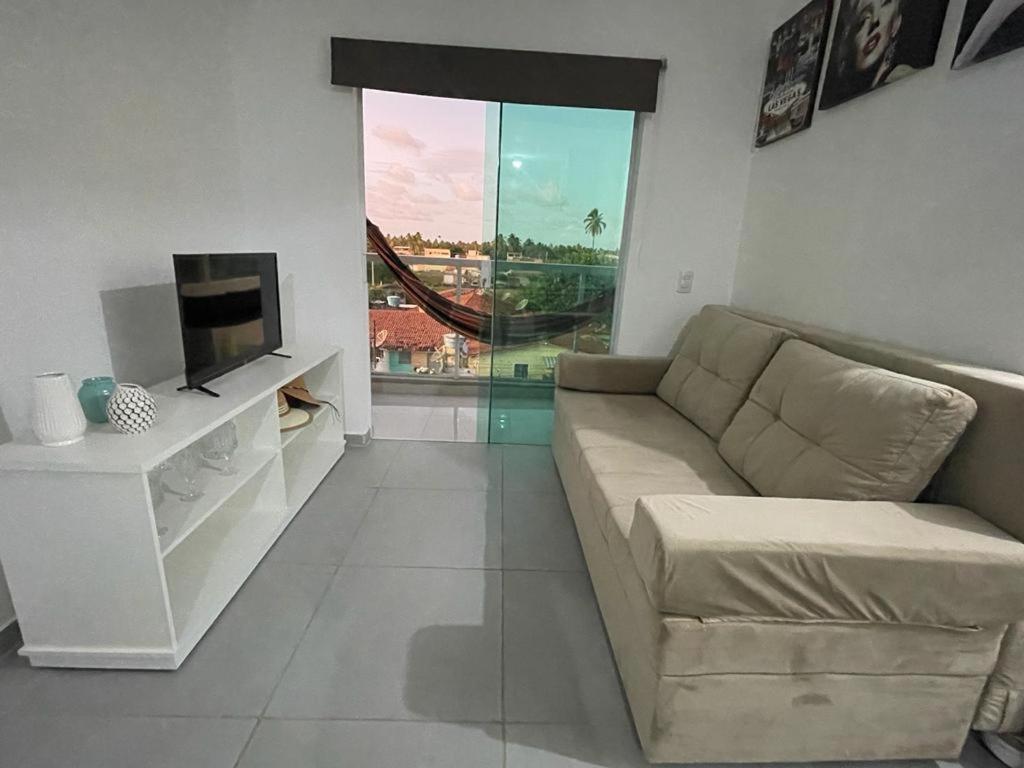 sala de estar con sofá y TV en APARTAMENTO EM PEROBA - MARAGOGI, en Maragogi