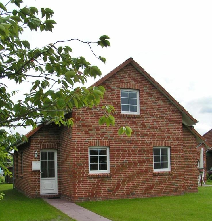 a red brick house with a white door and windows at Friesenstern in Norden