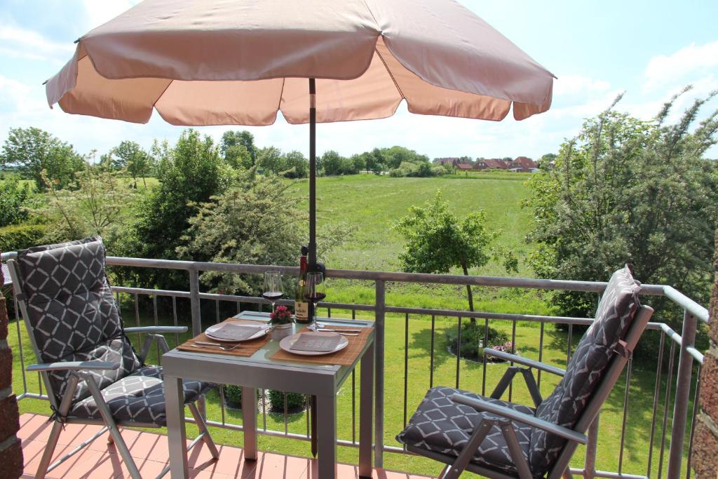 einen Tisch und zwei Stühle auf einer Terrasse mit einem Sonnenschirm in der Unterkunft Deichblick 2 in Greetsiel