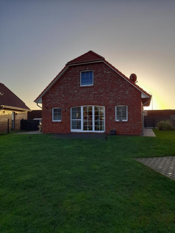 a red brick house with a large yard at Bei Ruhe in Loppersum