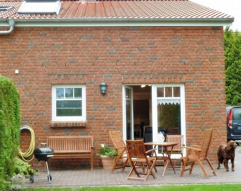 a brick house with a table and chairs and a dog at Gesine's Huuske in Eilsum