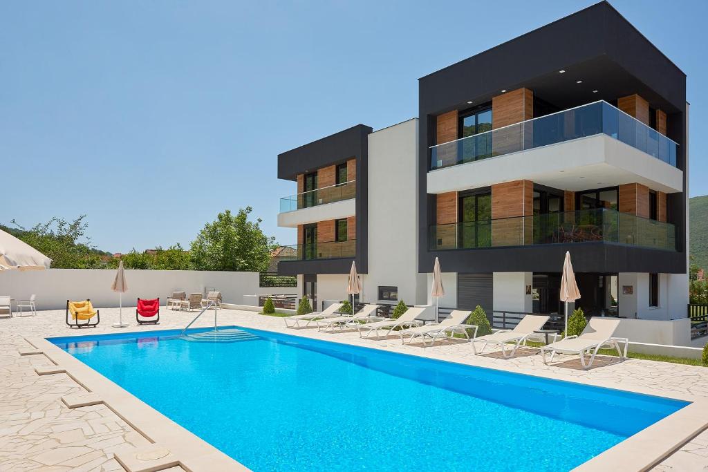 a building with a swimming pool in front of a building at Georgiy Lux Apartments in Lastva