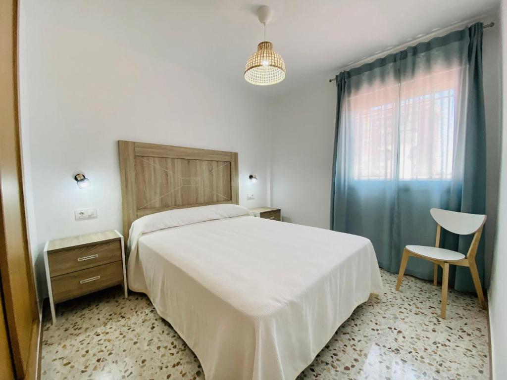 a bedroom with a bed and a chair and a window at Apartamentos Turísticos Santo Rostro in Chipiona