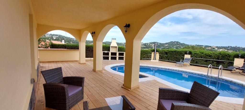 a patio with a swimming pool and two chairs and a swimming pool at LA VILLA DEL PARAISO in Vidreres