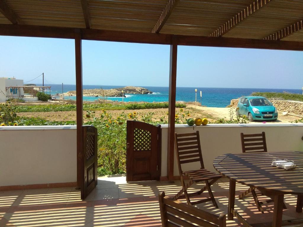 un patio con tavolo, sedie e vista sull'oceano di private beachfront house a Lefkos Karpathou