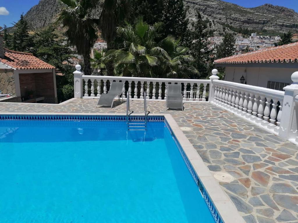 Valle de Abdalagís的住宿－Charming House with Pool & Barbecue，一座带白色围栏的房屋前的游泳池