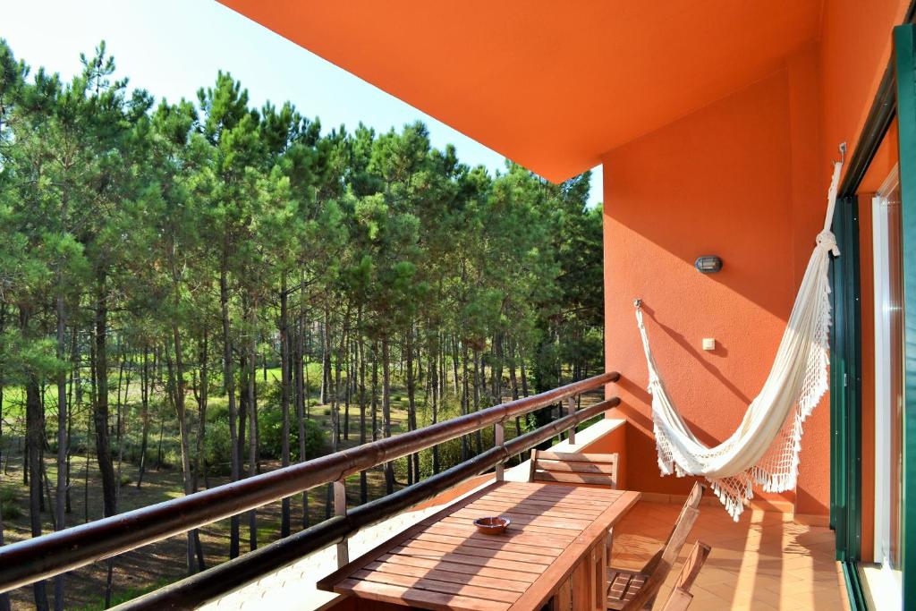 a hammock on a balcony with a view of trees at Apartamento Golf Resort in Charneca