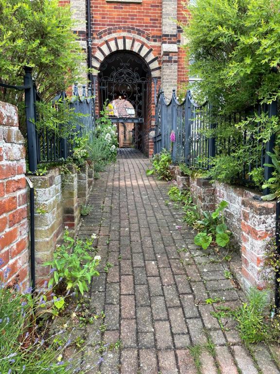 uma via de tijolos que leva a uma entrada para um edifício com um portão em Cobwebs em Kedington