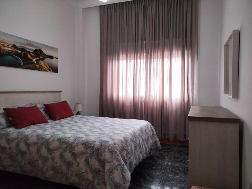 sypialnia z łóżkiem z czerwonymi poduszkami i oknem w obiekcie APARTAMENTOS La PEÑA A w mieście La Guancha