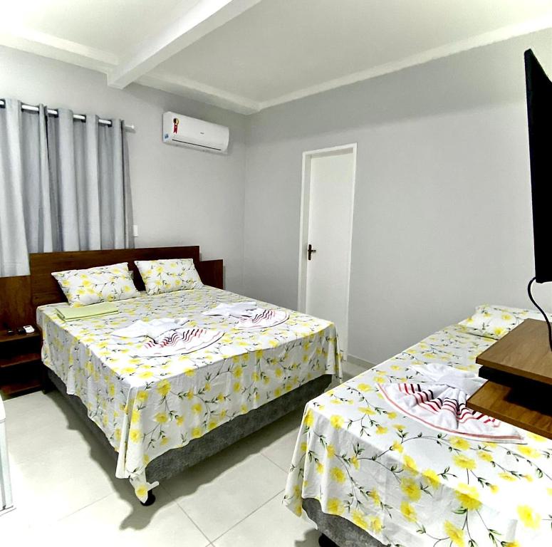 a bedroom with two beds and a table and a window at Pousada Sertaneja in Canindé de São Francisco