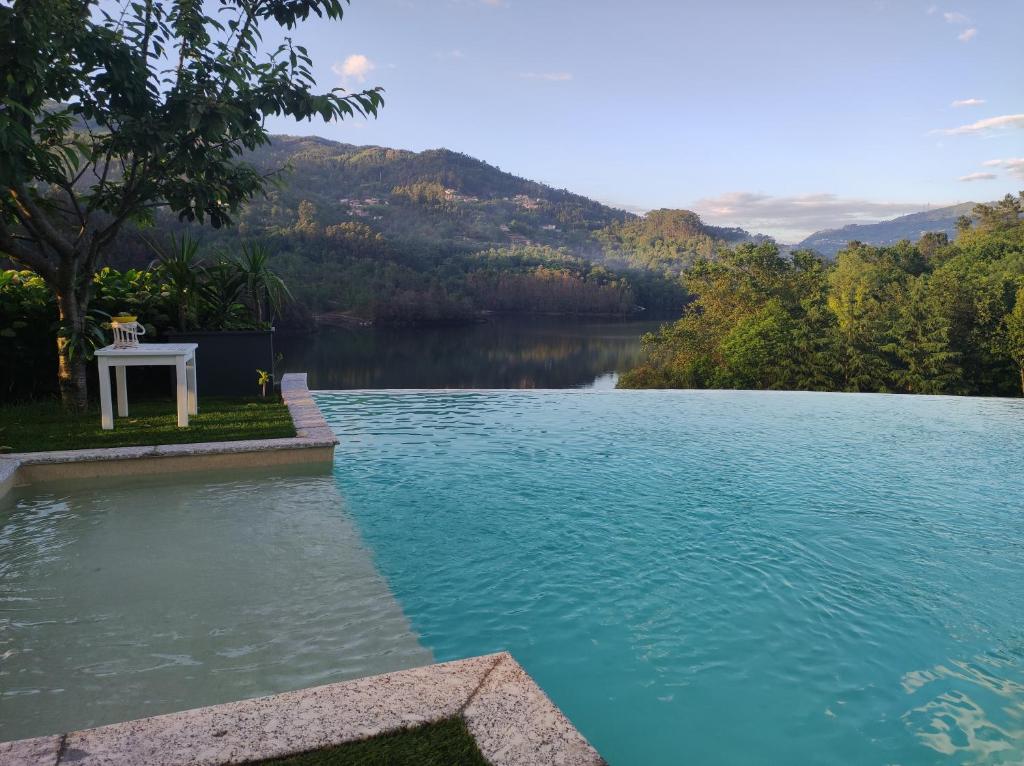 ヴィエイラ・ド・ミーニョにあるEira House - Quinta de Fundevilaのテーブルと湖のある水のプール