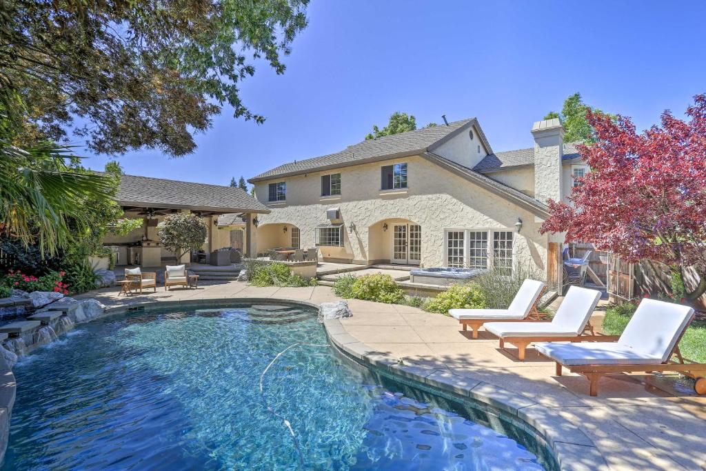 a swimming pool with chairs and a house at Redding Getaway with Hot Tub and Outdoor Kitchen! in Redding