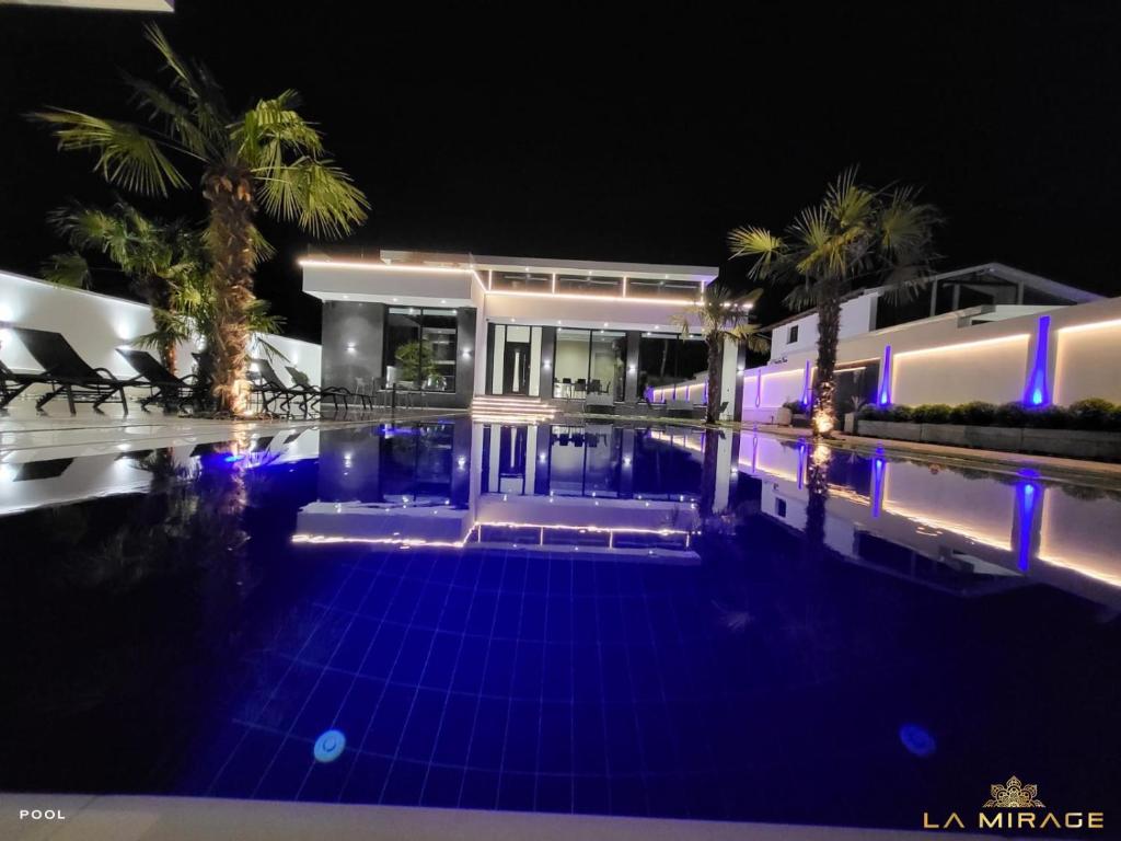 Rrushkull的住宿－La Mirage Villa，夜间在房子前面的游泳池