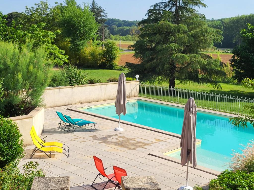 a swimming pool with chairs and umbrellas next to it at Le Clos des Figuiers - 3 Gîtes de caractère in Duravel