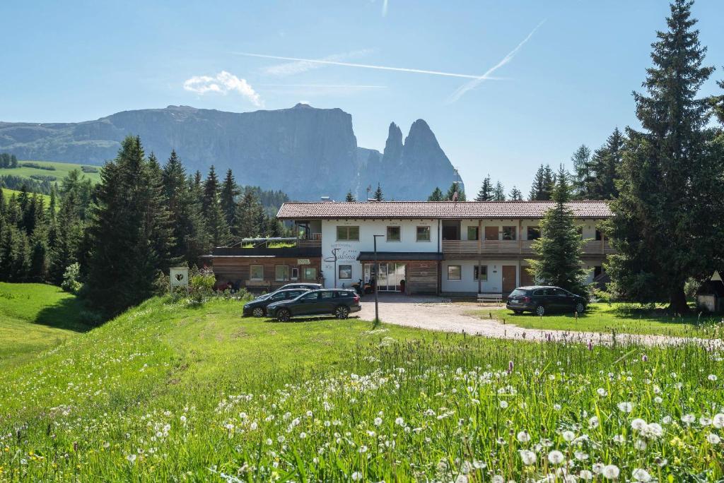 a building with cars parked in a field of flowers at Ferienparadies Sabina Föhre in Alpe di Siusi