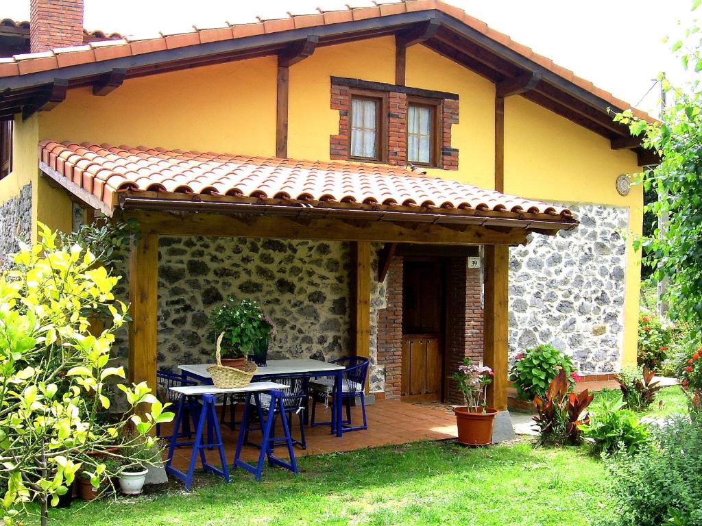 un patio con mesa y sillas frente a una casa en La casita de las flores, en Monte Miravalles