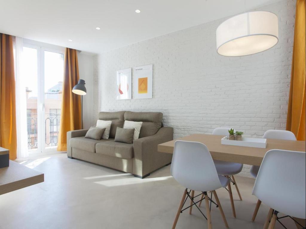 Sunny Playa Apartment في برشلونة: غرفة معيشة مع أريكة وطاولة وكراسي