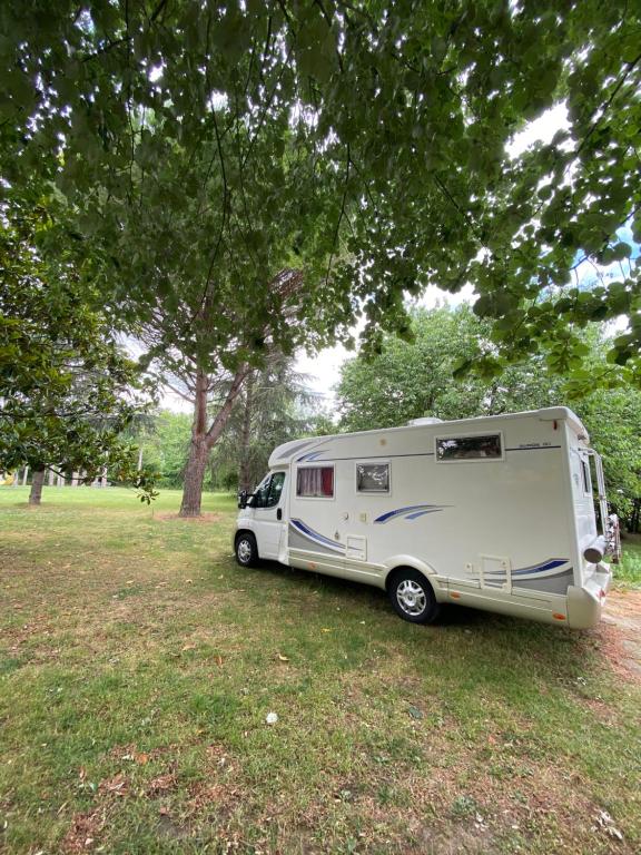 a white caravan parked in a field under a tree at Camping car Canal du Midi in Montesquieu-Lauragais