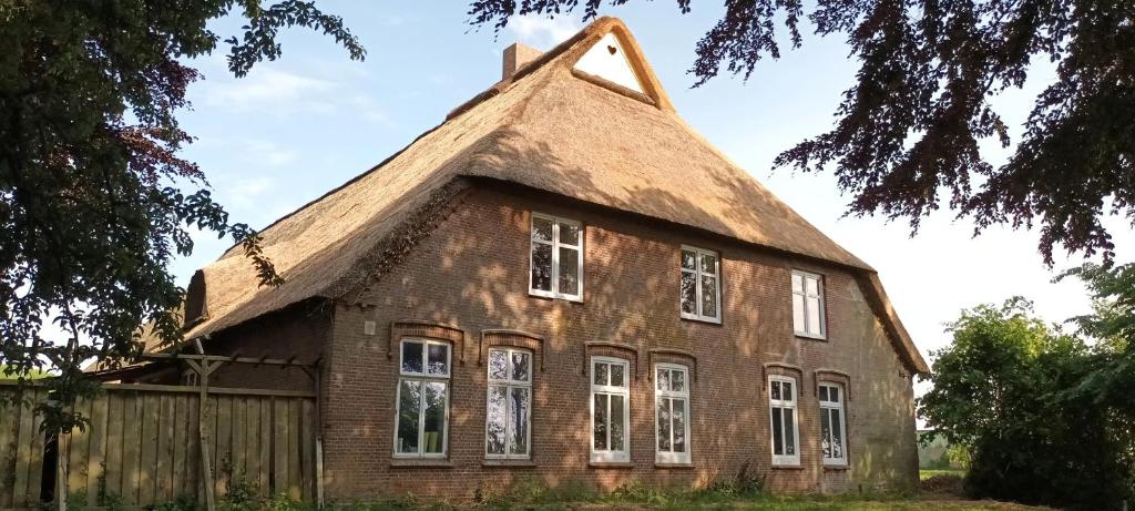 De Olle Uhlhoff في Barlt: منزل من الطوب القديم مع سقف من القش