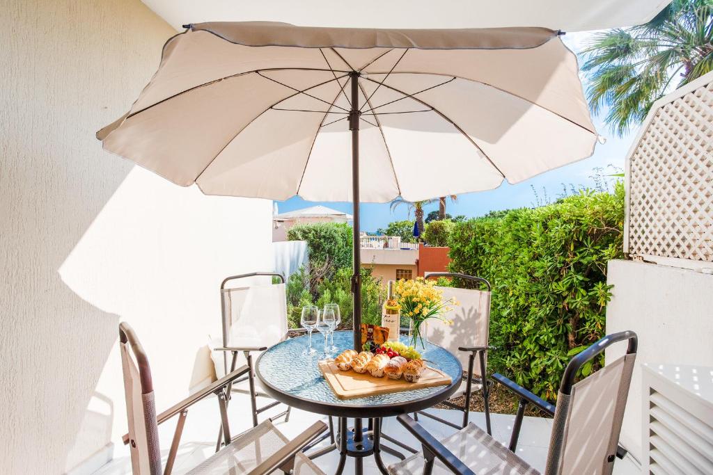 een tafel en stoelen met een parasol op een balkon bij L'ANGE GARDIEN III AP4293 By Riviera Holiday Homes in Villefranche-sur-Mer