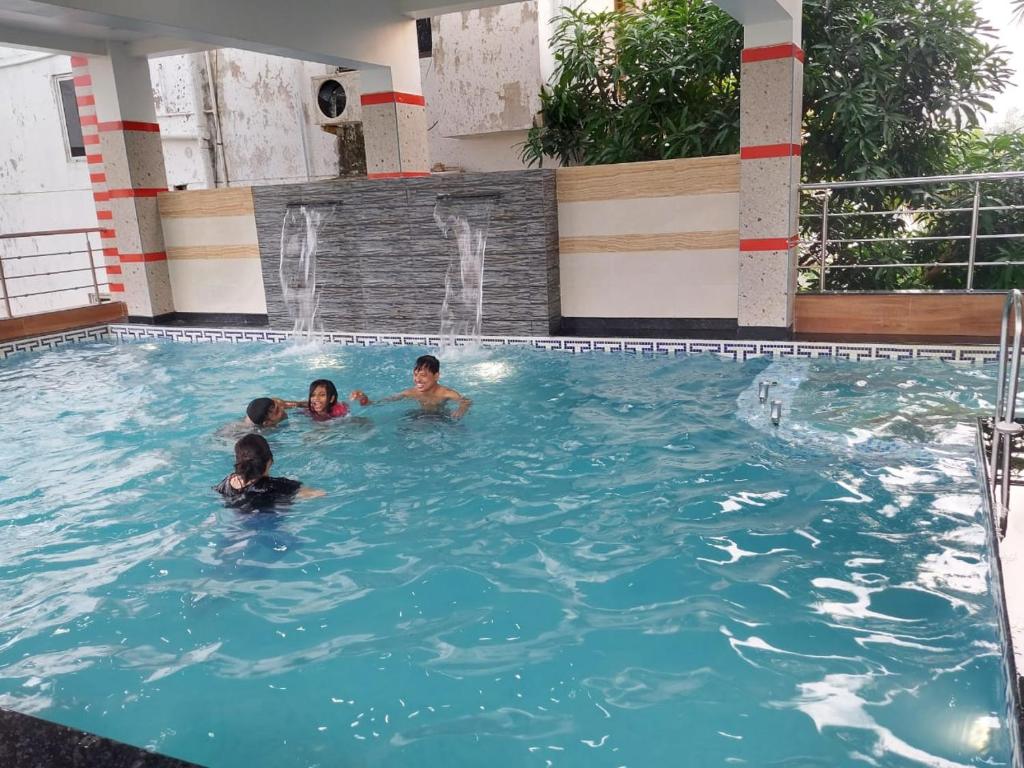 a group of people swimming in a swimming pool at Blue Stone Hotel & Restaurant Mandarmani in Mandarmoni