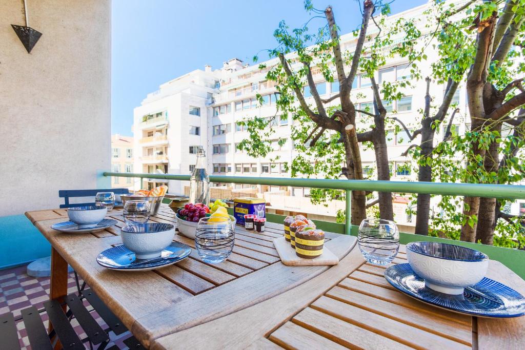 une table en bois avec des bols de nourriture sur un balcon dans l'établissement LE TIVOLI II AP4282 By Riviera Holiday Homes, à Nice