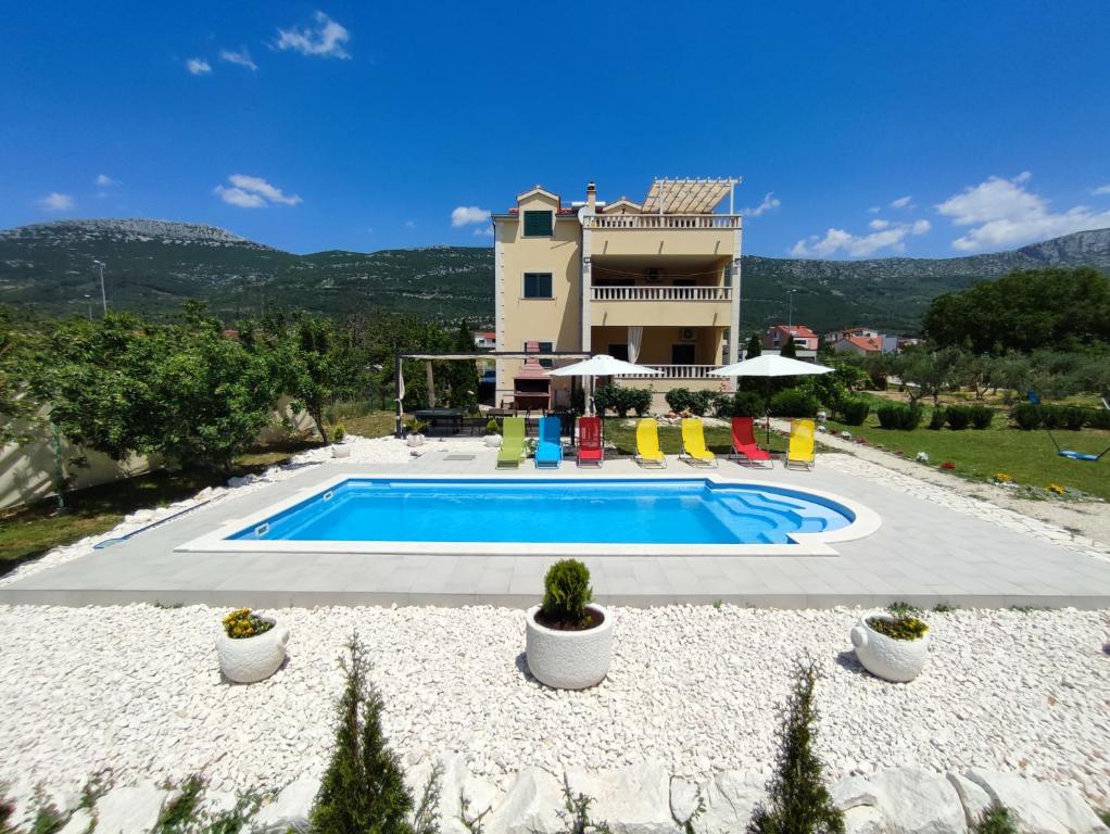una villa con piscina di fronte a una casa di Apartments Maris a Kaštela (Castelli)