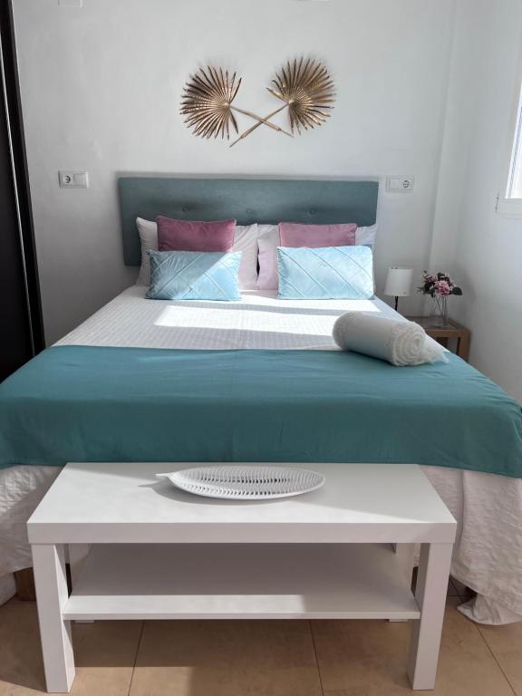 un lit avec une tête de lit bleue et une table blanche dans l'établissement Estudio Montañar a 50 metros del mar, à Jávea