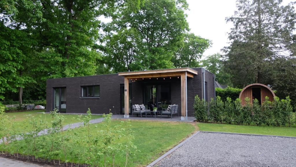 a black house in a yard with a garden at The White Oak - Luxe 4 persoons bungalow met prive sauna in Voorthuizen